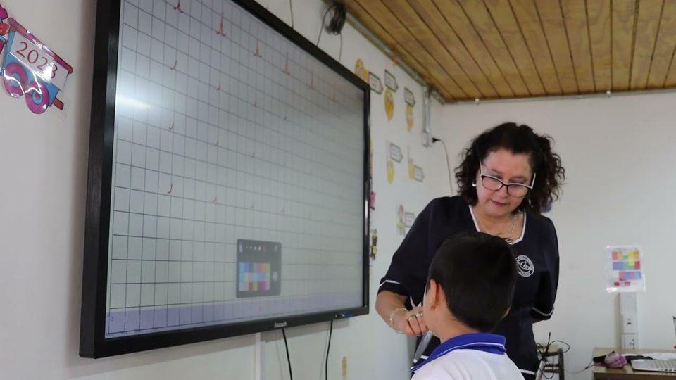 Profesora Viviana Oyanedel trabajando con un alumno frente a la pantalla Edutouch