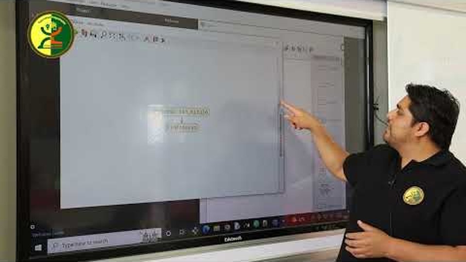 Profesor Julio Mollo señalando contenido en la pantalla Edutouch